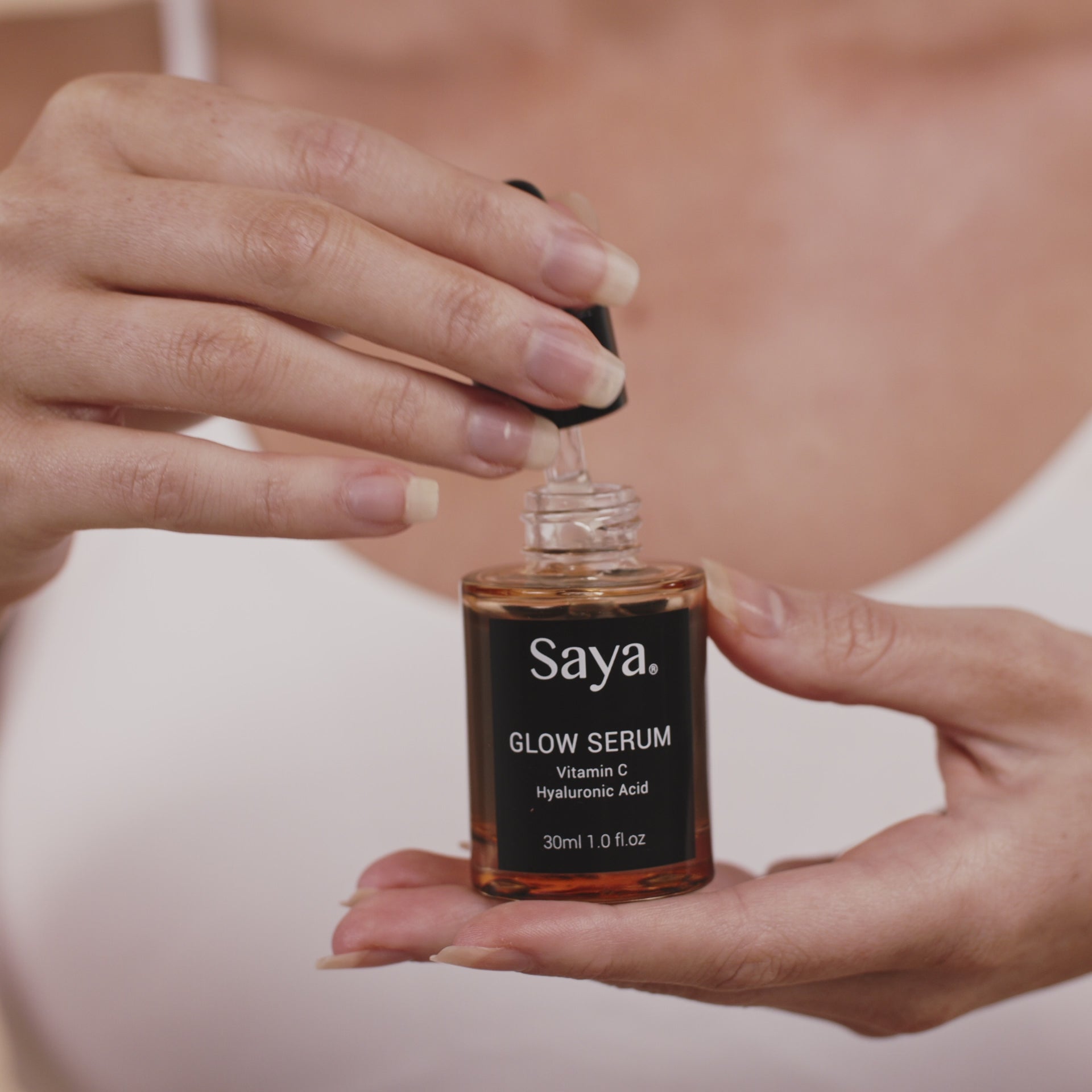 a video of a woman using saya glow serum on her face