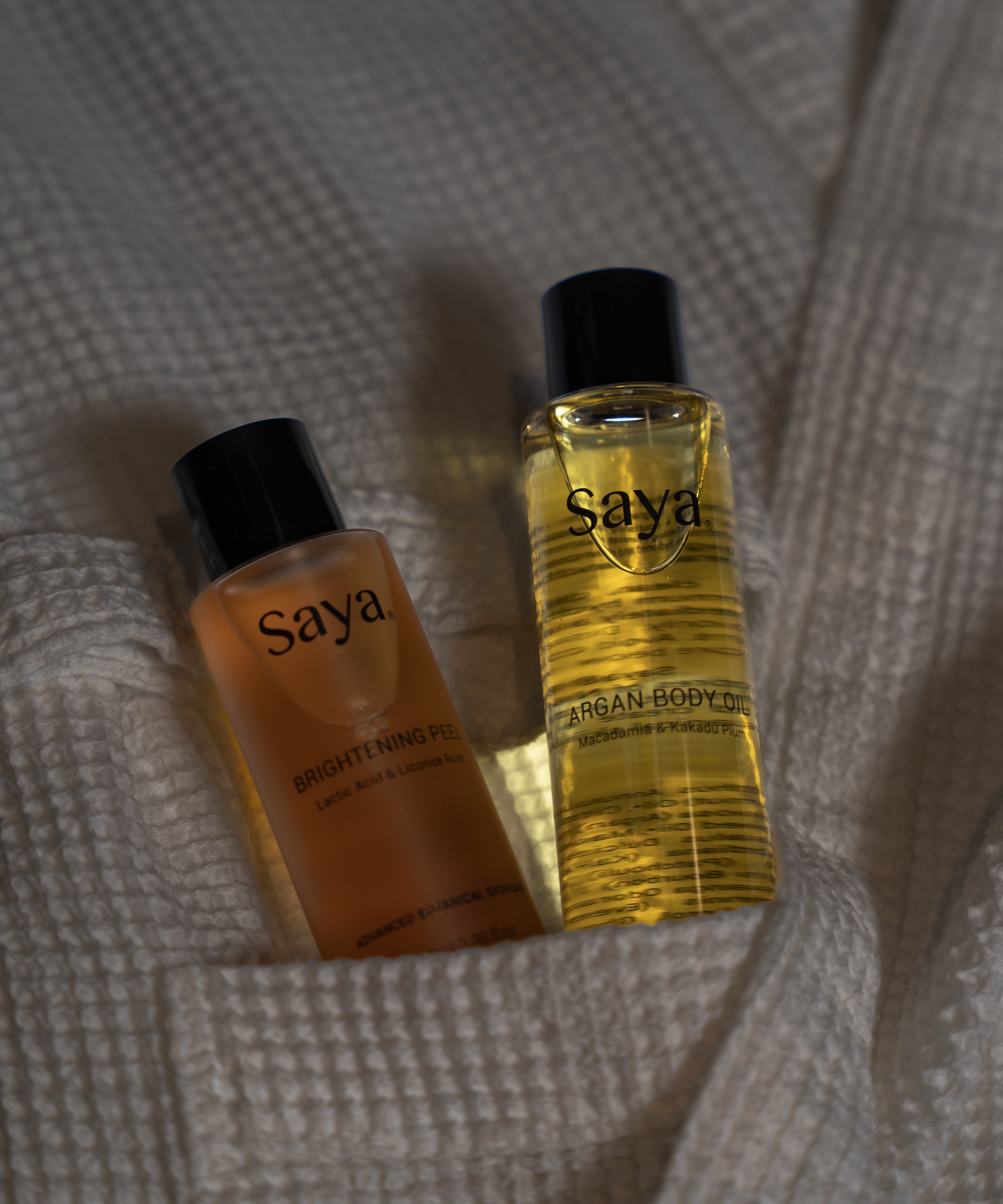 a bottle of saya argan body oil and brightening peel in a bathrobe pocket