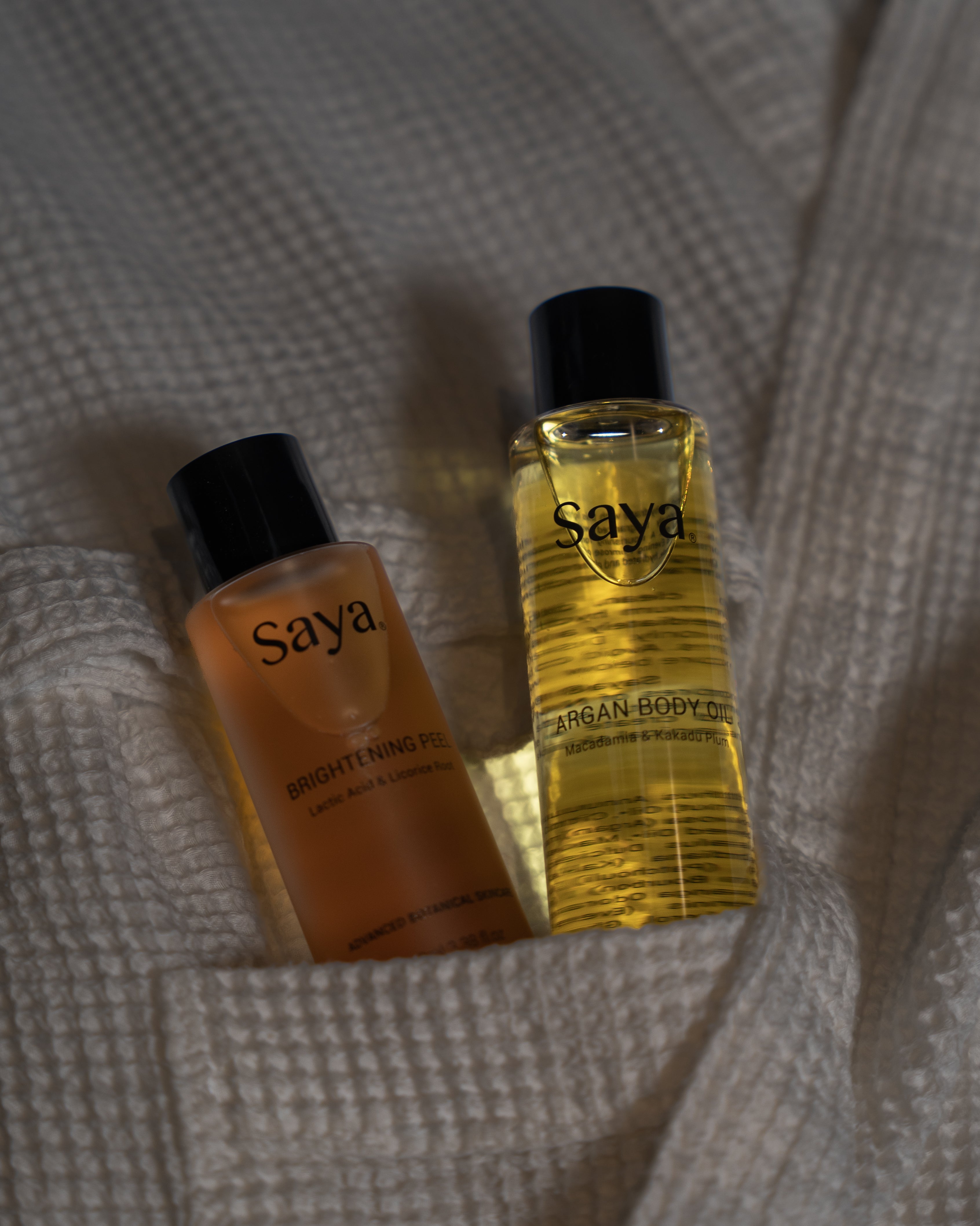 a bottle of saya argan body oil and brightening peel in a bathrobe pocket