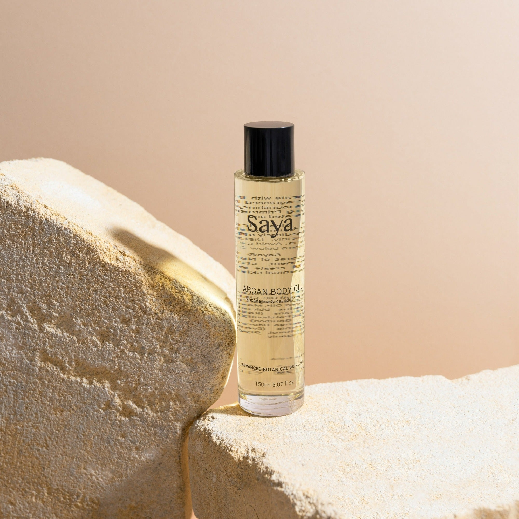 a bottle of saya argan body oil on a rock
