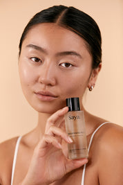 a woman holding a bottle of saya brightening peel