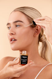 a woman applying saya glow serum on her face with the dropper 
