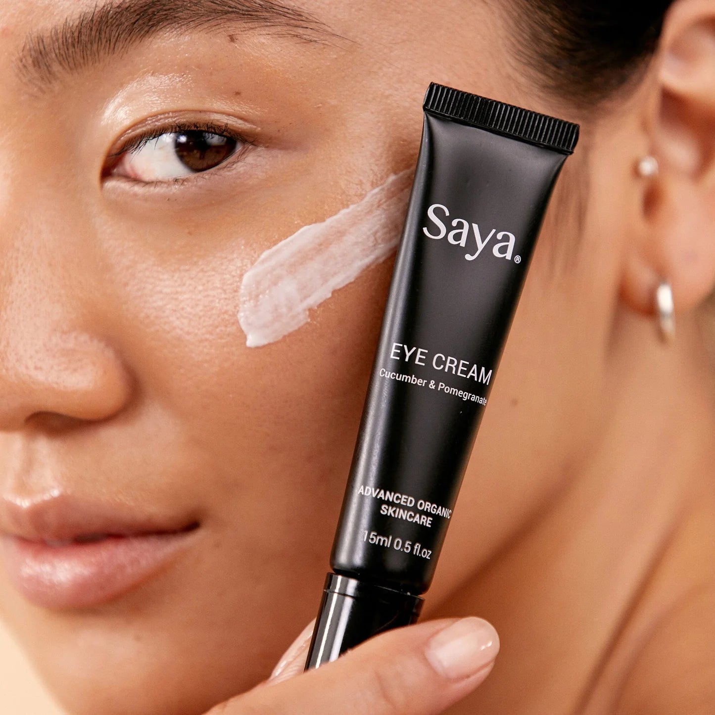 a woman holding a tube of saya eye cream