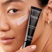 a woman holding a tube of saya eye cream