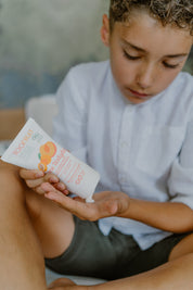 a boy squeezing toofruit creme bodydoux on his palm