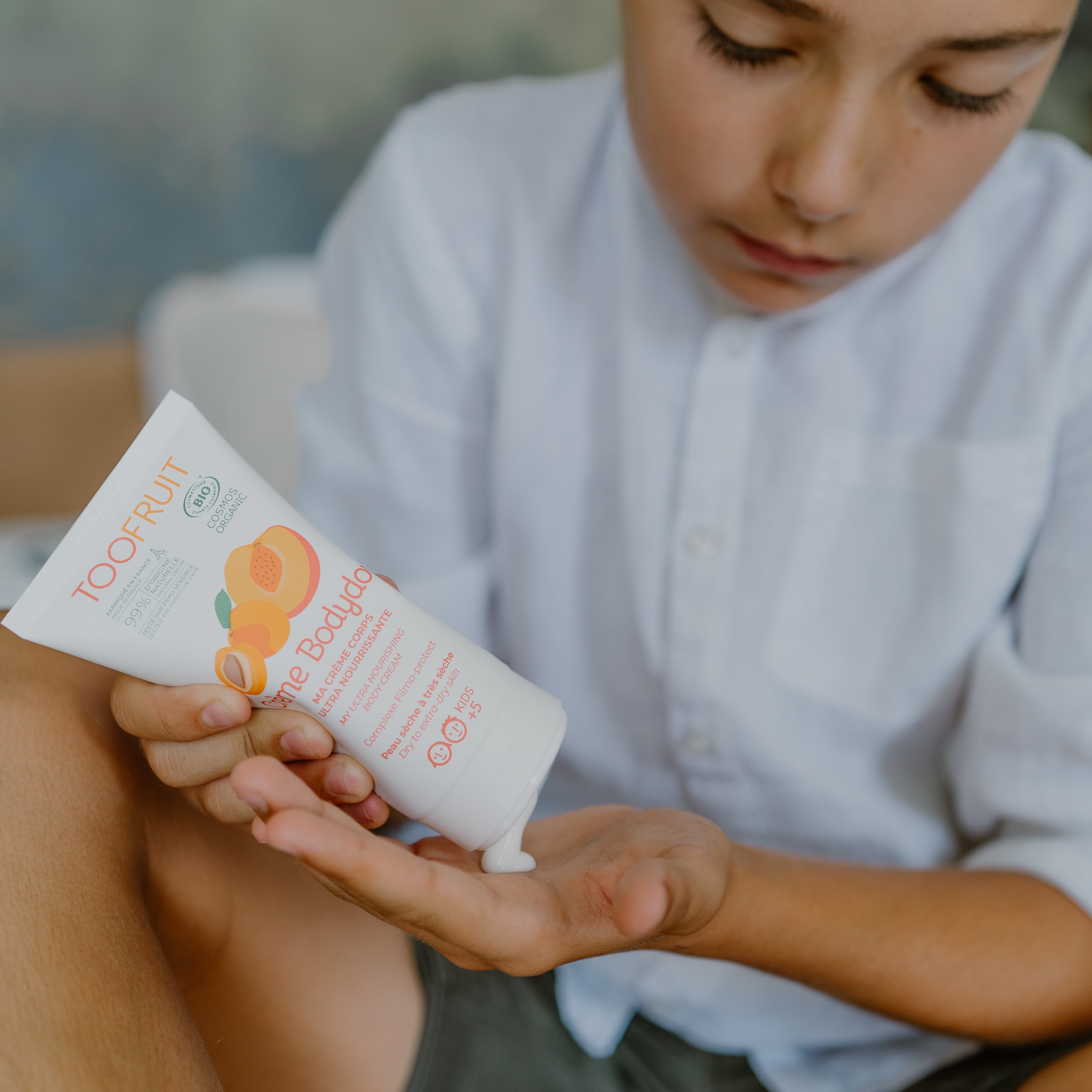a boy squeezing toofruit creme bodydoux on his palm