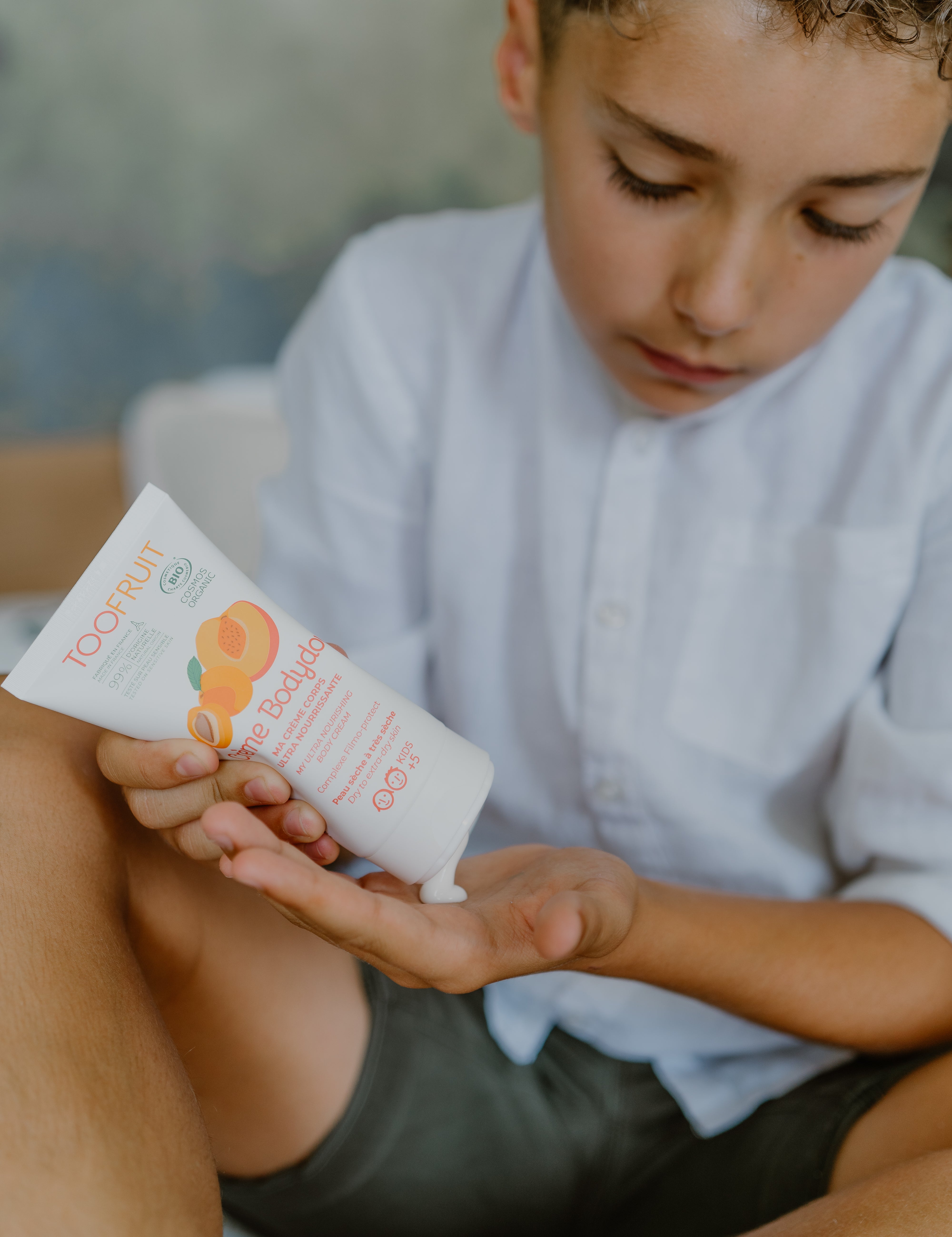 a boy squeezing toofruit creme bodydoux on his palm