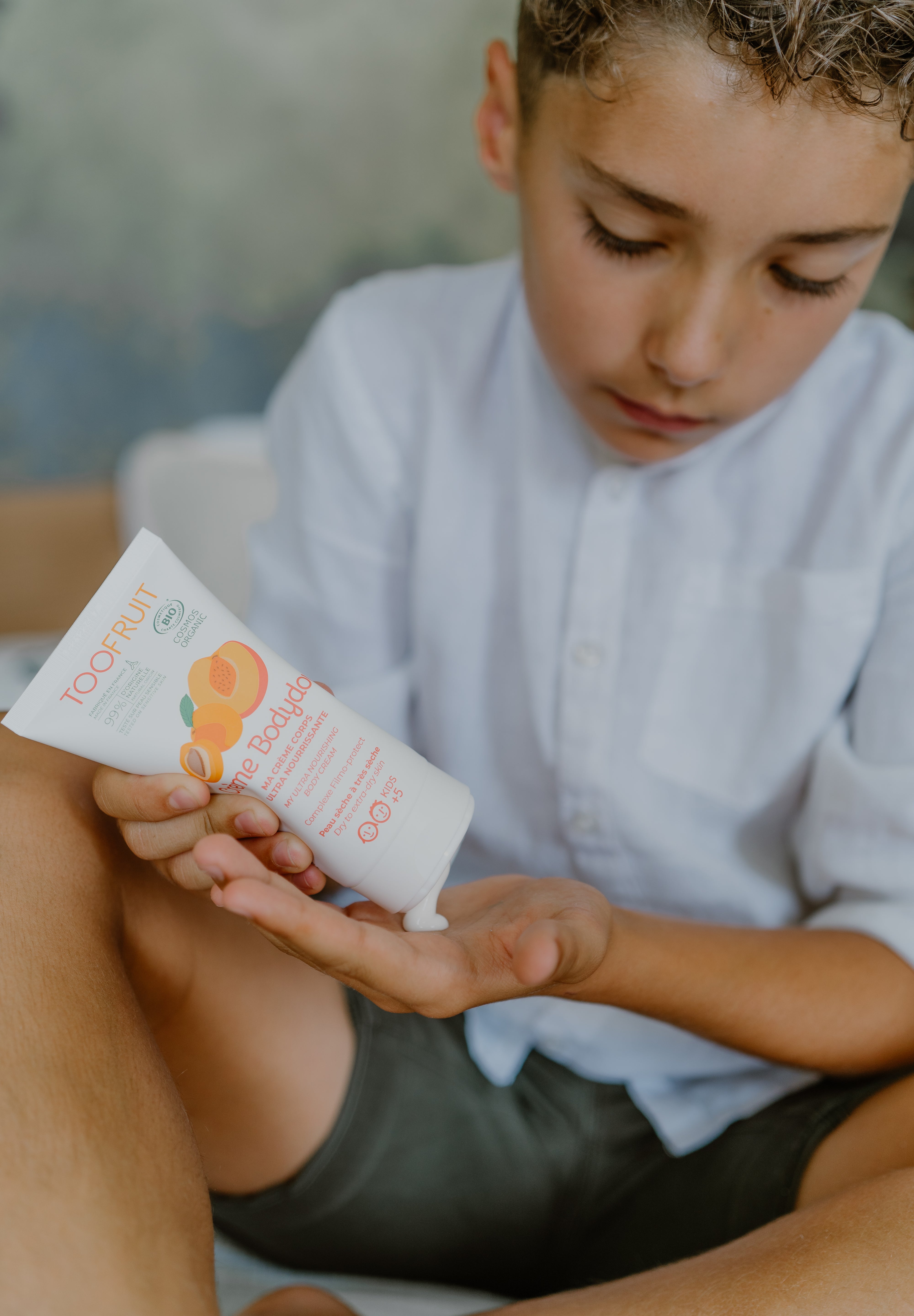 a boy squeezing toofruit creme bodydoux on his palm