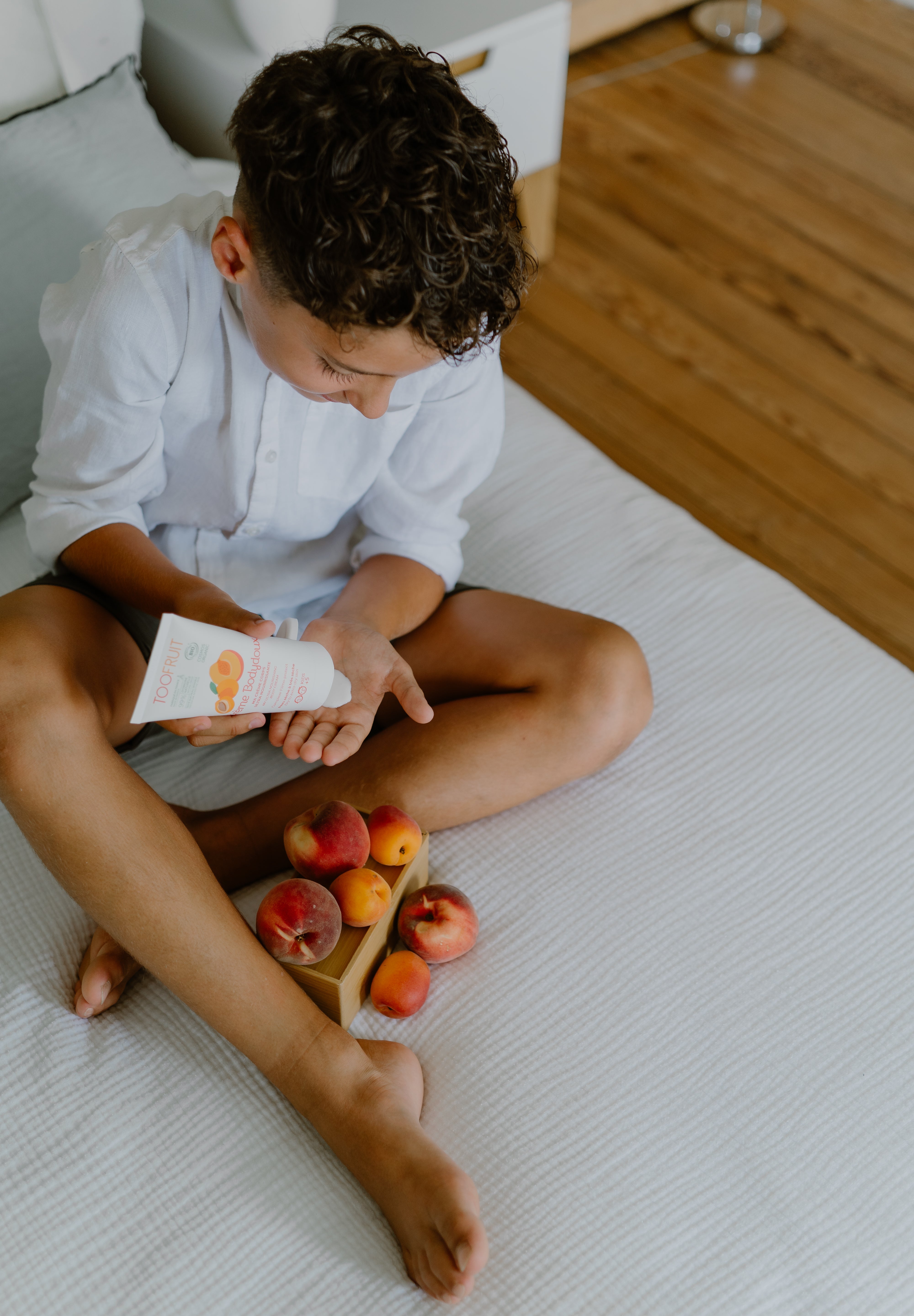 a boy squeezing toofruit creme bodydoux on his palm