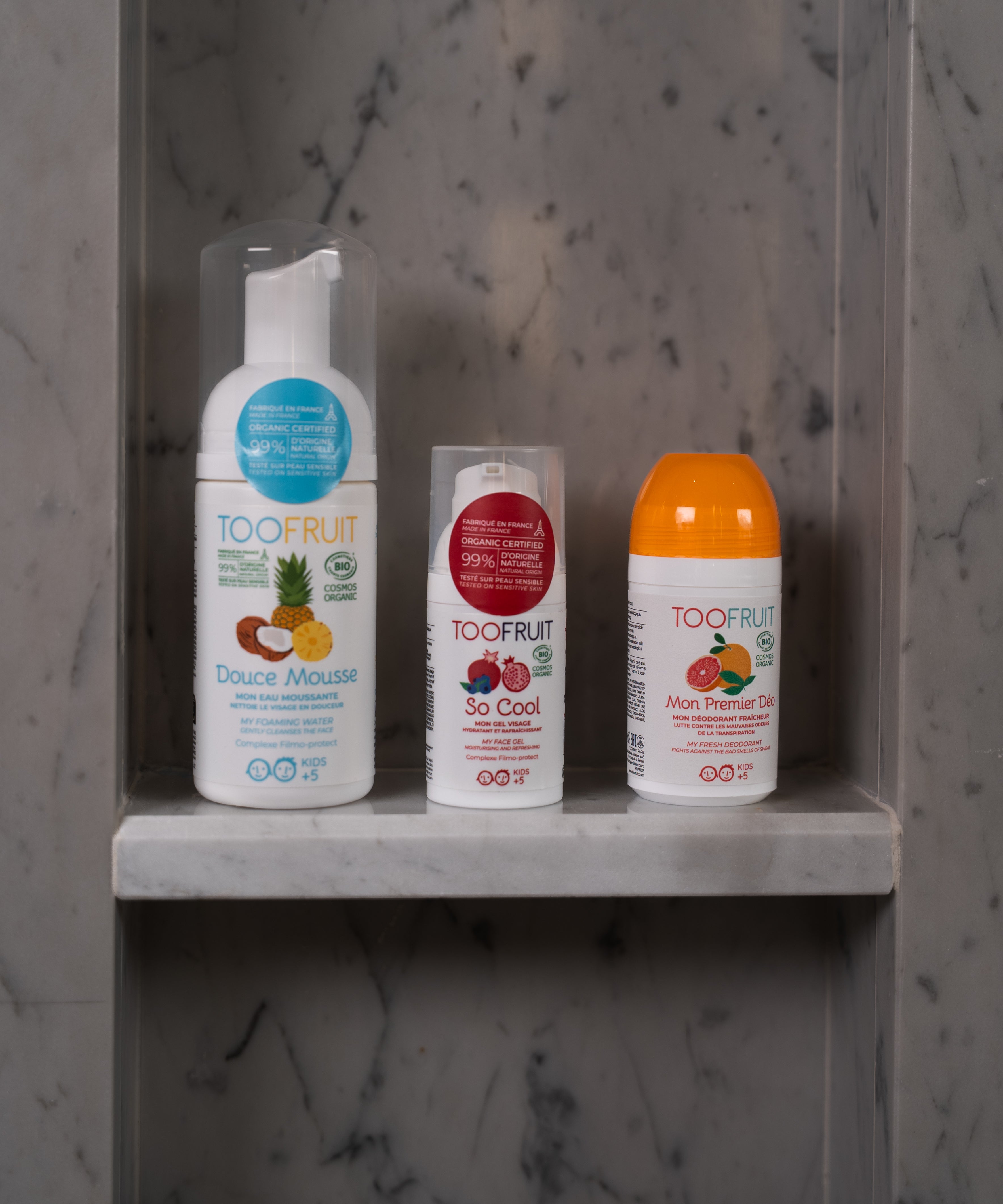 a bottle of toofruit douce mousse, so cool and grapefruit deodorant on a bathroom ledge