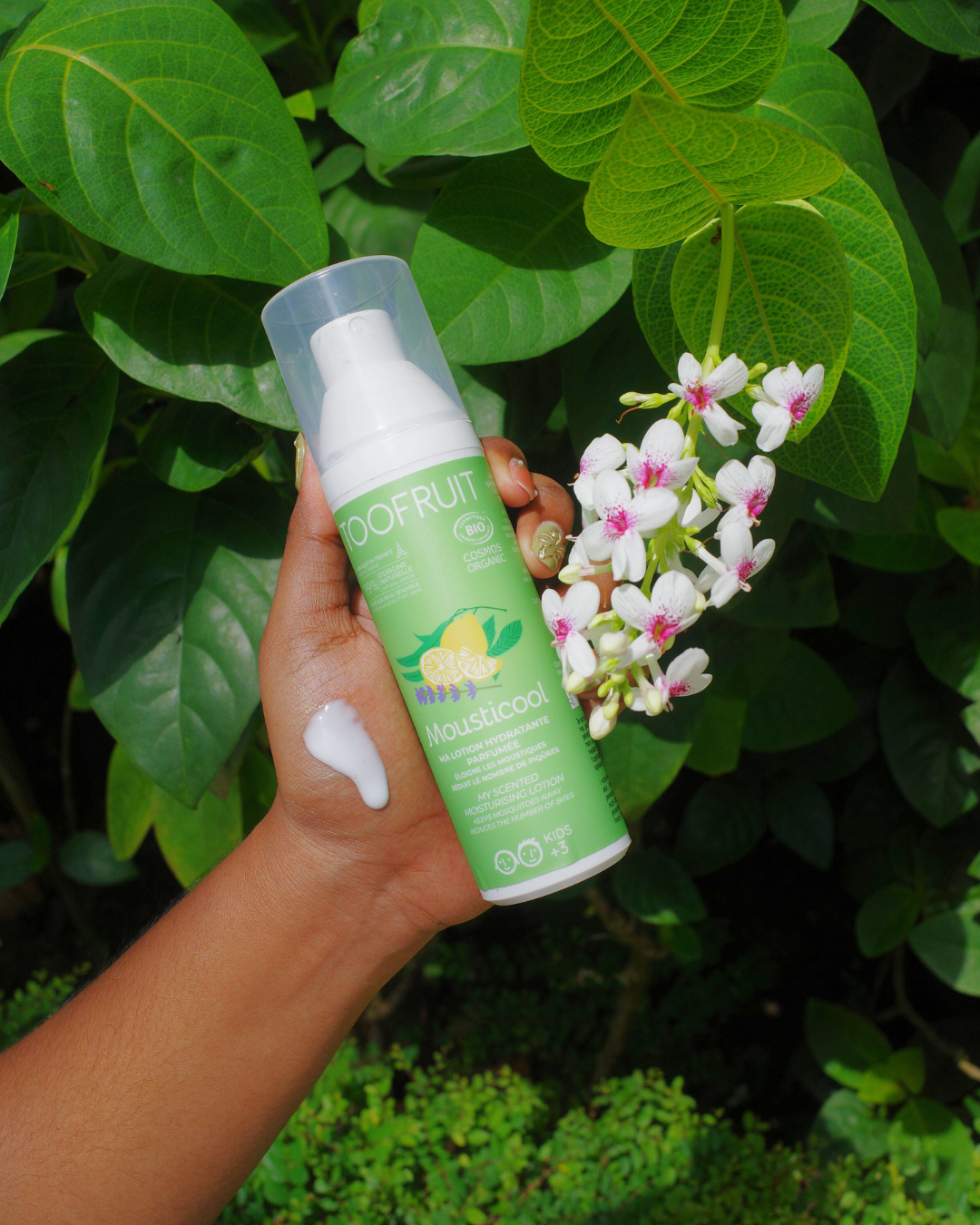 a hand holding a bottle of toofruit mousticool lotion