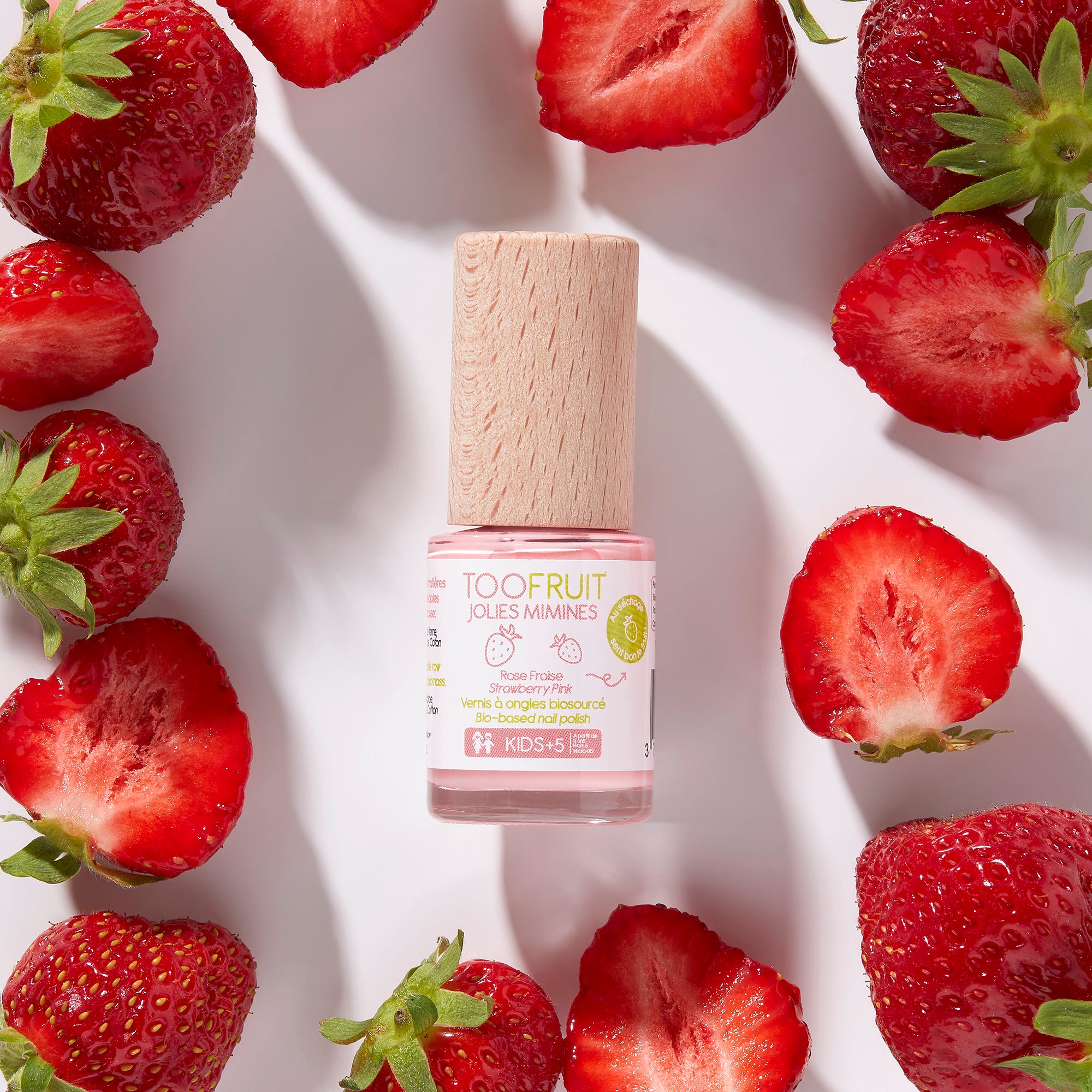 a bottle of toofruit strawberry nail polish and strawberries