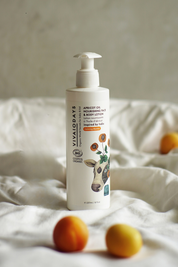 a large bottle of vivaiodays apricot face and body lotion with pump on the bed with apricots