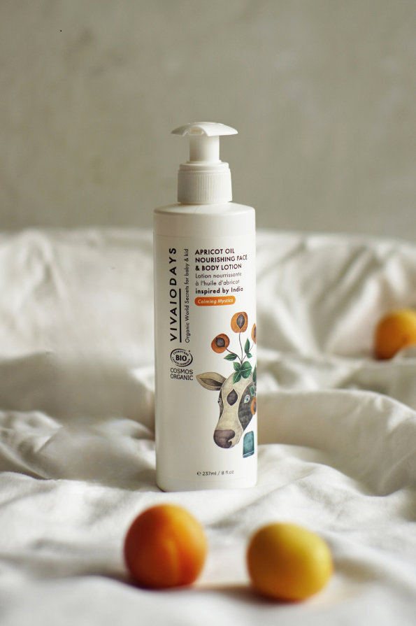 a large bottle of vivaiodays apricot face and body lotion with pump on the bed with apricots