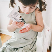 a girl squeezing a tube of vivaiodays apricot face and body lotion on her hand