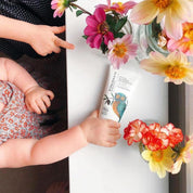 a baby's hand holding a tube of vivaiodays olive oil balm gel